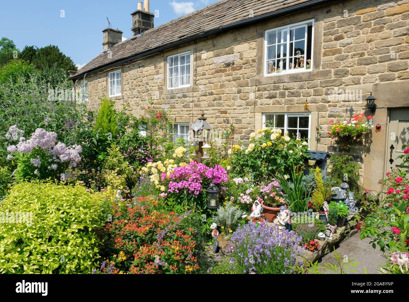 A cottage garden in the Derbyshire plague village of Eyam. Colourful flowers stand against stone built walling. Stock Photo