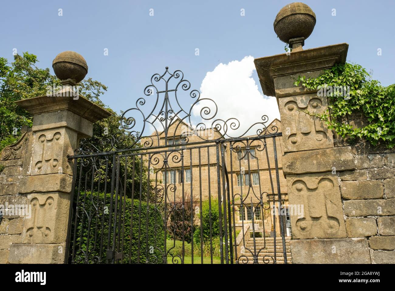 Distinctive gates to the Hall in the Derbyshire plague village of Eyam. Wrought iron gates and huge stone pillars provide an impressive entrance. Stock Photo