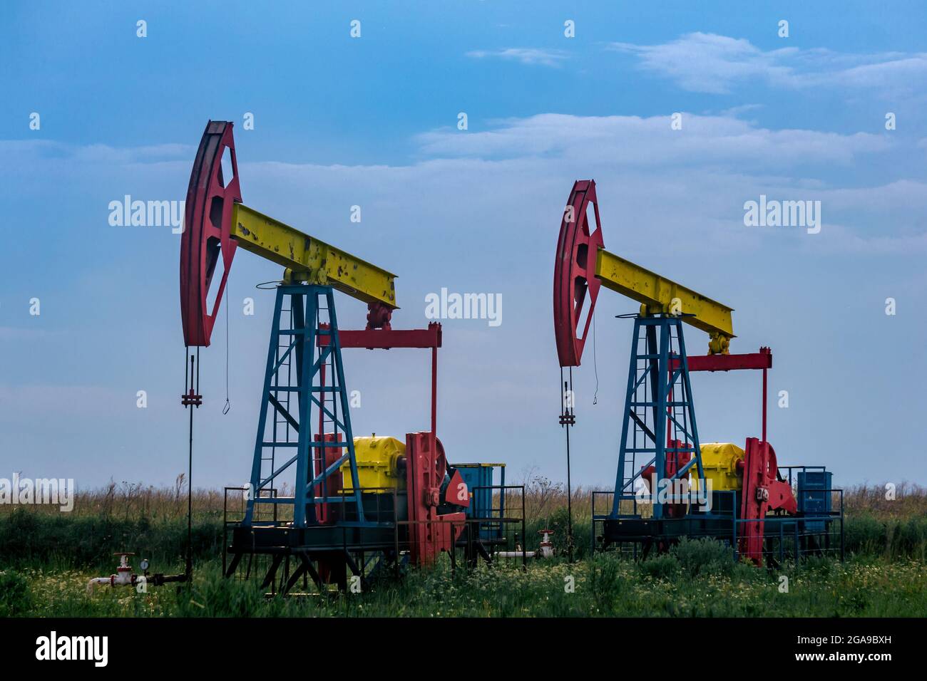 pumpjacks piston pumps operating at an oil well in field outdoors Stock
