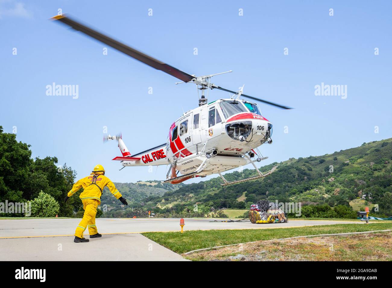 A CalFire from Alma Helitack firefighter directs a incoming CalFire Huey during slingload training in preparation for the 2019 Wildfire Season Stock Photo