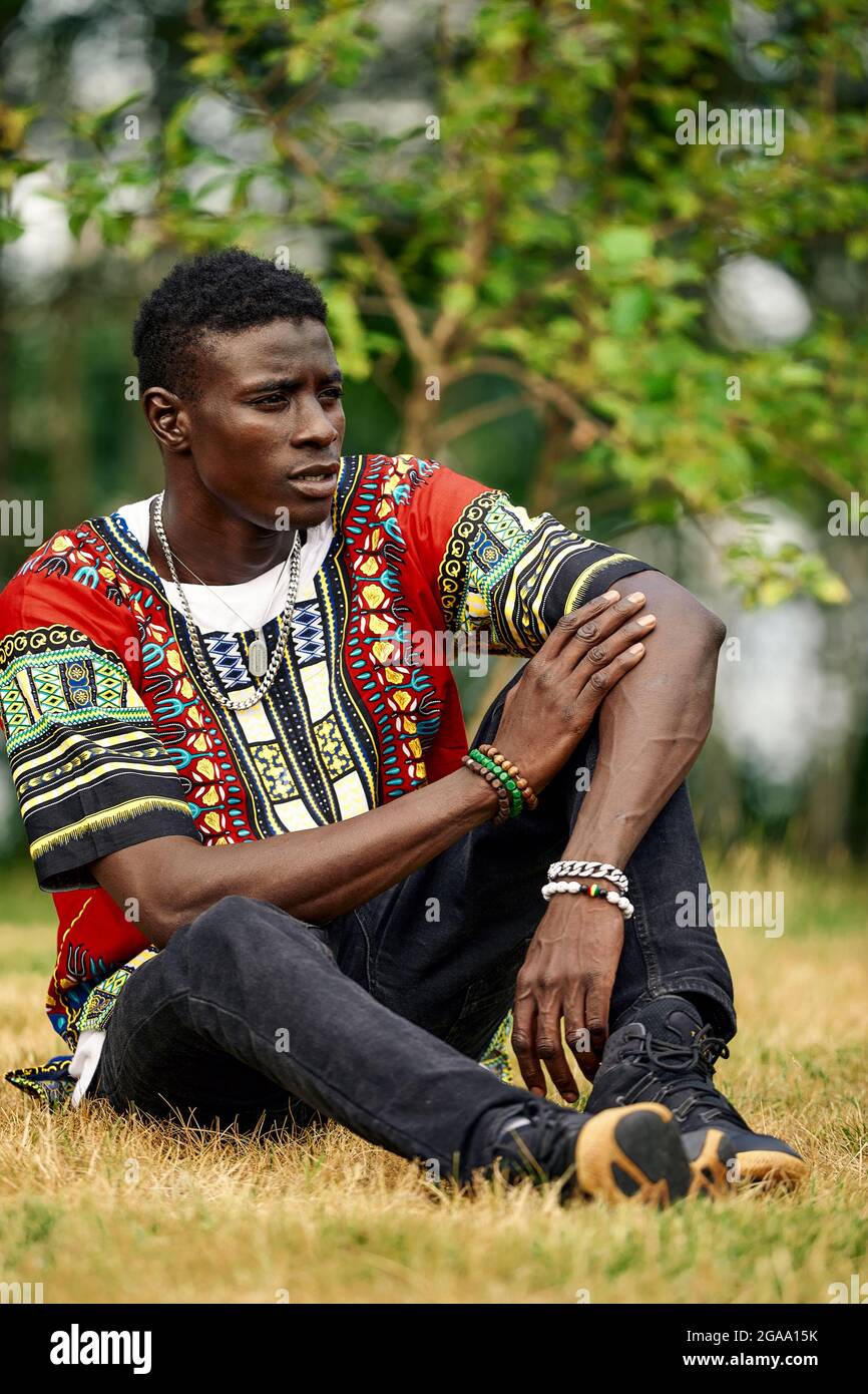An African man in South African national clothes, a black young man resting in a park in national clothes Stock Photo