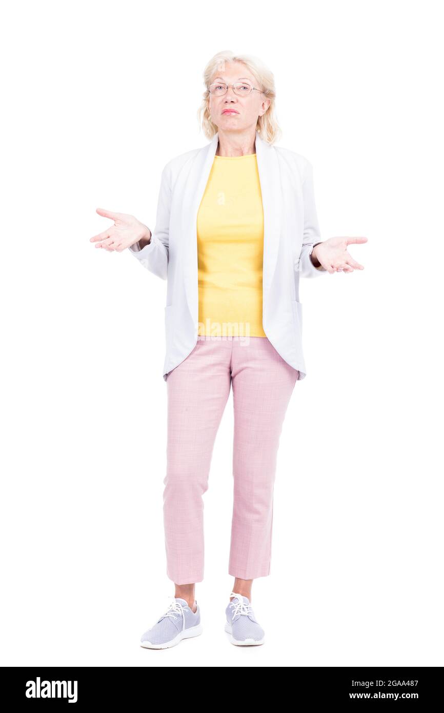 Vertical full shot of modern senior woman standing against white background feeling uncertain about something Stock Photo