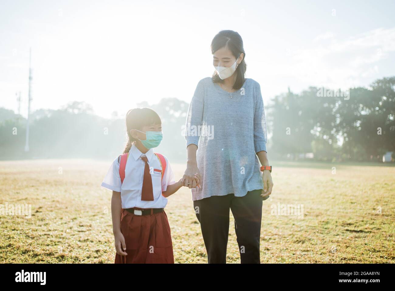 mother and her daughter walking together and wear face mask Stock Photo