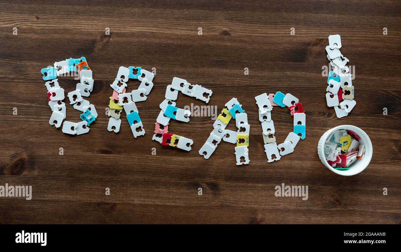 Top down view of the word bread made of bread bag tags, against a wooden background. Stock Photo