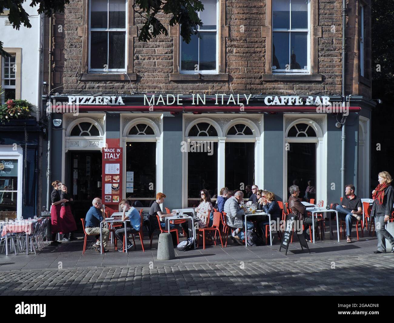 Edinburgh, Scotland:  A warm sunny day allows people to enjoy outdoor dining at an Italian restaurant in the historic Grassmarket area. Stock Photo