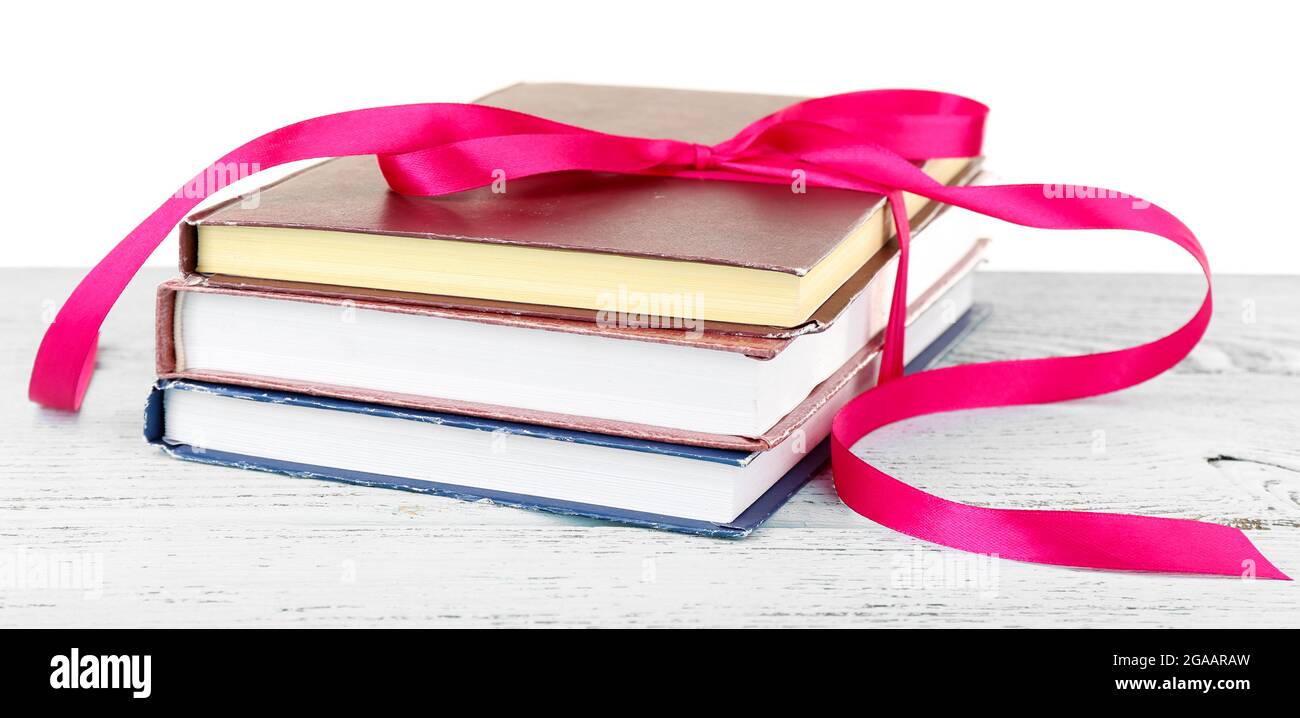 Stack of books with ribbon on table isolated on white Stock Photo