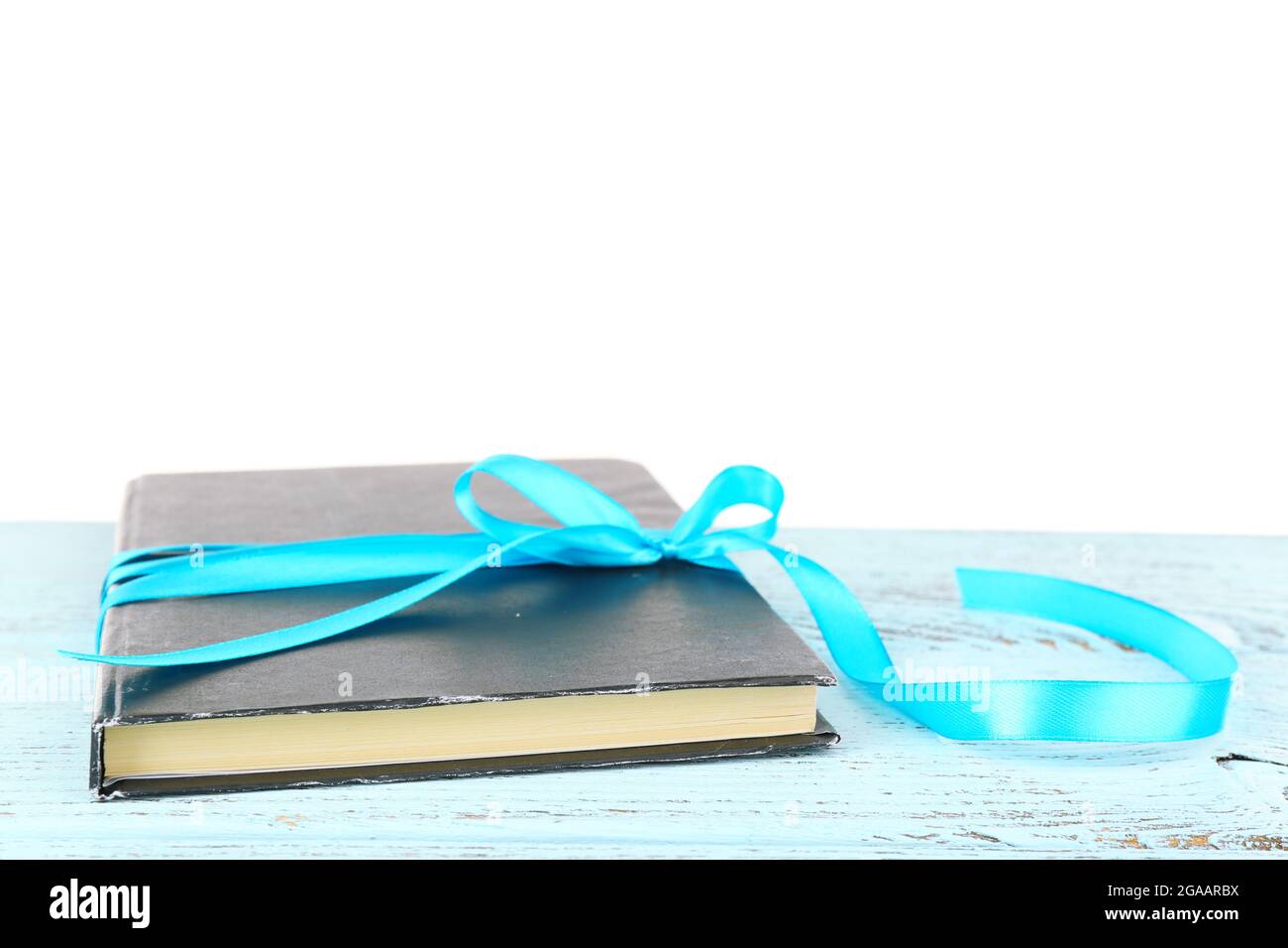Book wrapped with color ribbon on table isolated on white Stock Photo ...