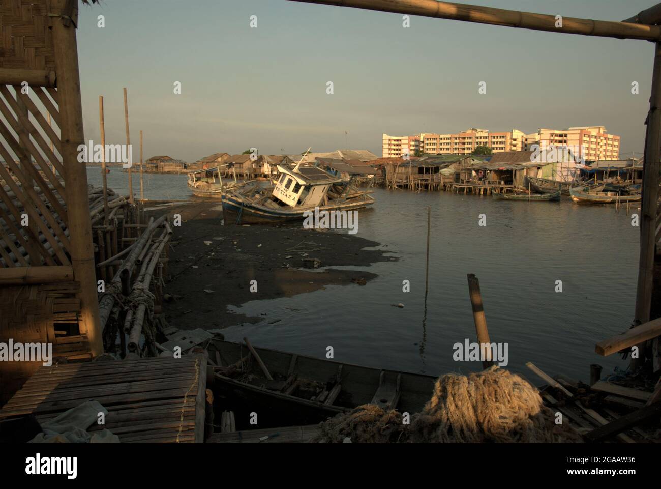 Intertidal beach and stilt houses in a background of new flat buildings in the coastal village of Marunda in Cilincing, Jakarta, Indonesia. Stock Photo
