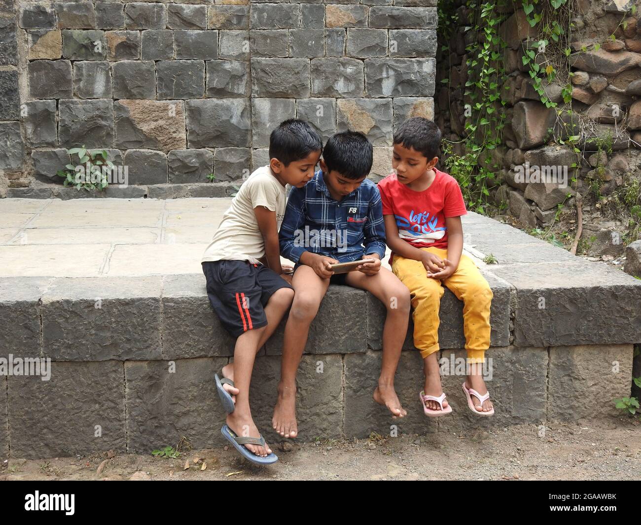 17 July 2021, Maharashtra, India, Little Indian kids playing with cellphone. Stock Photo