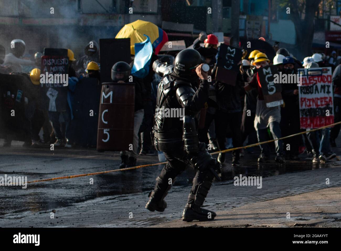 Medellin, Colombia. 28th July, 2021. A Colombia's riot police officer throws a tear gas grenade to demonstrators as demonstrations ended in late-night clashes between Colombia's riot police (ESMAD) and Demonstrators as Colombia marks 3 months of Anti-Government Protests against Colombia's president Ivan Duque government, and a new tax-reform amidst unrest and violence that left at least 83 dead since protests started. On July 28, 2021 in Medellin - Antioquia, Colombia. Credit: Long Visual Press/Alamy Live News Stock Photo