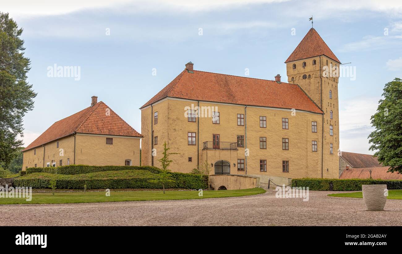 a gravel road leading up to a big yellow castle in three floors with a tall tower, Tosterup, Sweden, July 16, 2021 Stock Photo