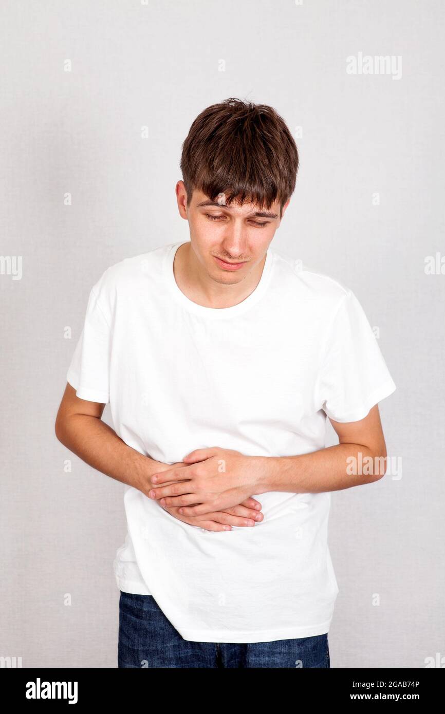 Young Man feels Stomach Ache on the White Wall Background Stock Photo
