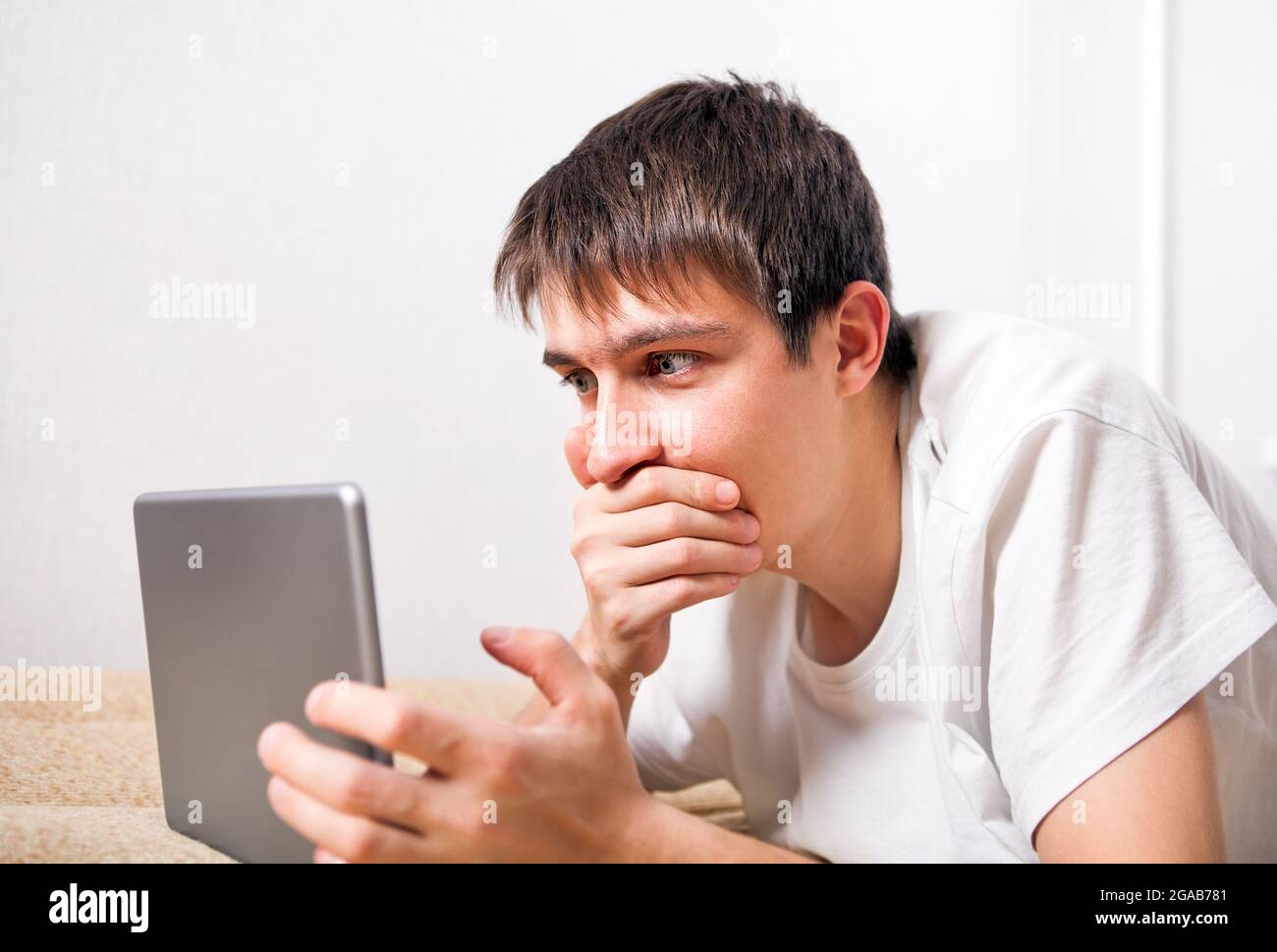 Surprised Young Man with Tablet Computer at the Home Stock Photo