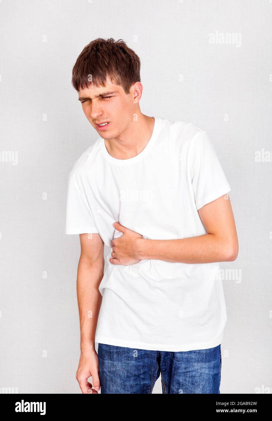 Young Man with Stomach Ache on the White Wall Background Stock Photo