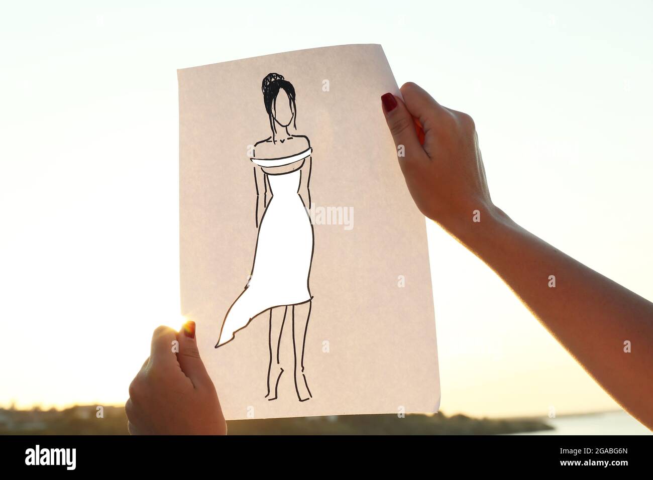 Drawing woman in cutout dress on sheet of paper on nature