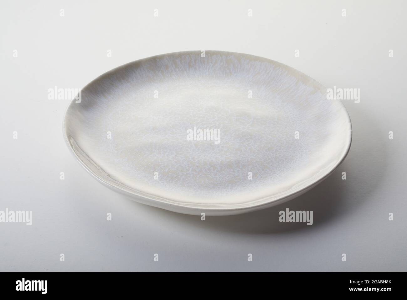 High angle of round clean plate covered with uneven stained enamel and placed on gray table Stock Photo