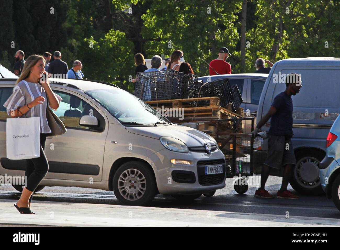 Junk dealer pushes his cart among cars in the center of Athens Stock