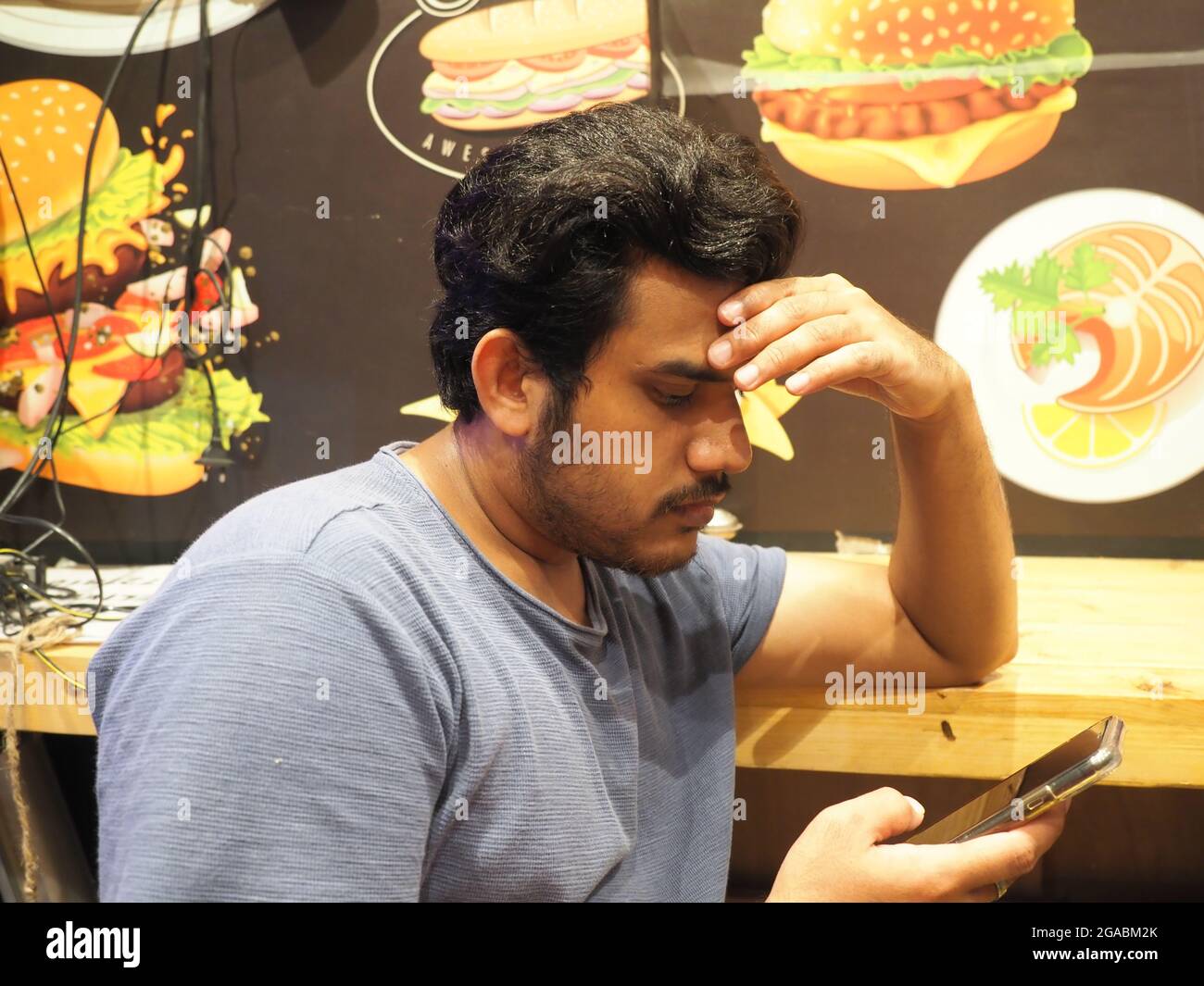 KOLKATA, INDIA - Jul 23, 2021: Man using iphone in cafe located in kolkata india. Focus on mobile phone Stock Photo