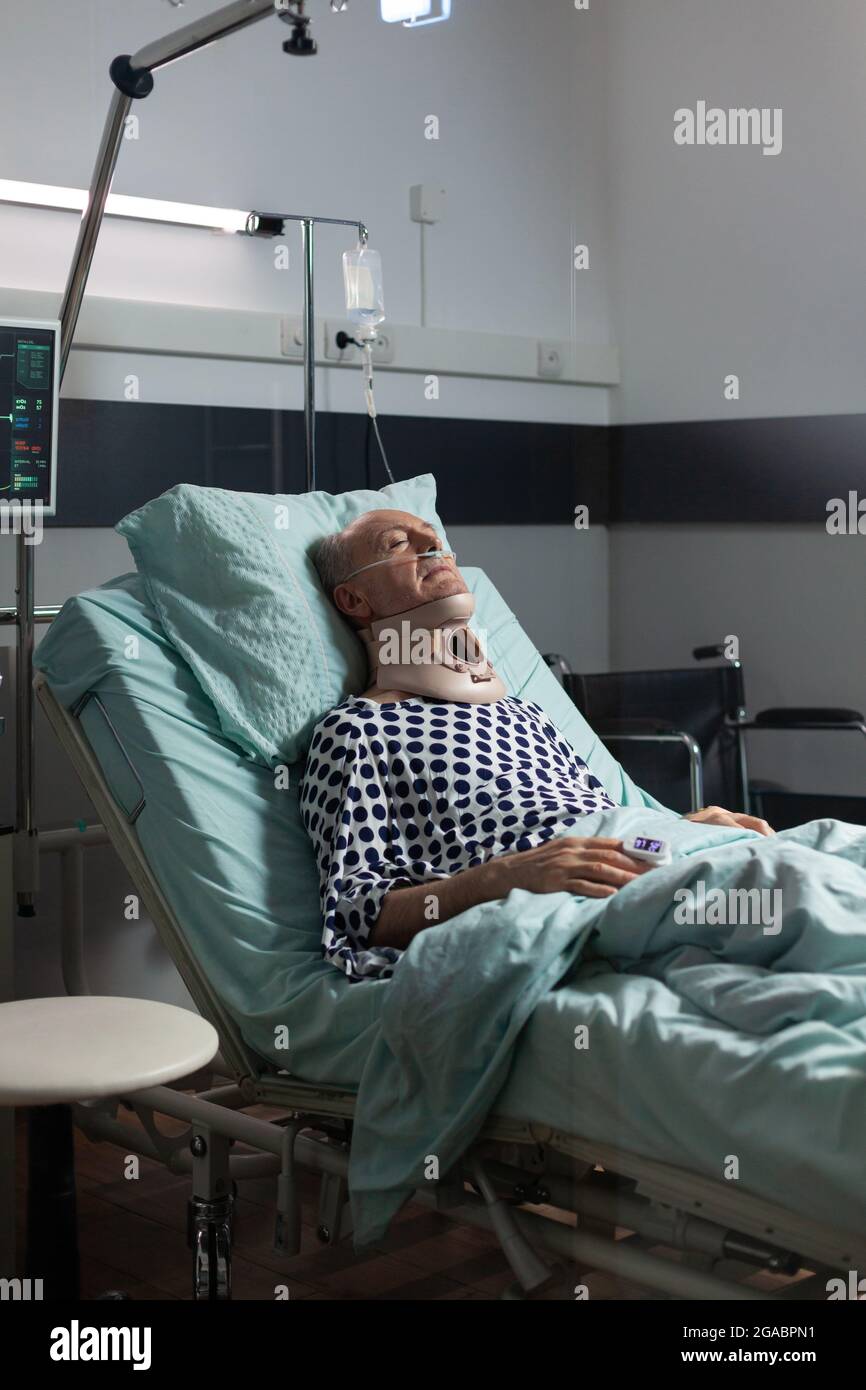 Senior man suffering after serious accident laying in hospital bed