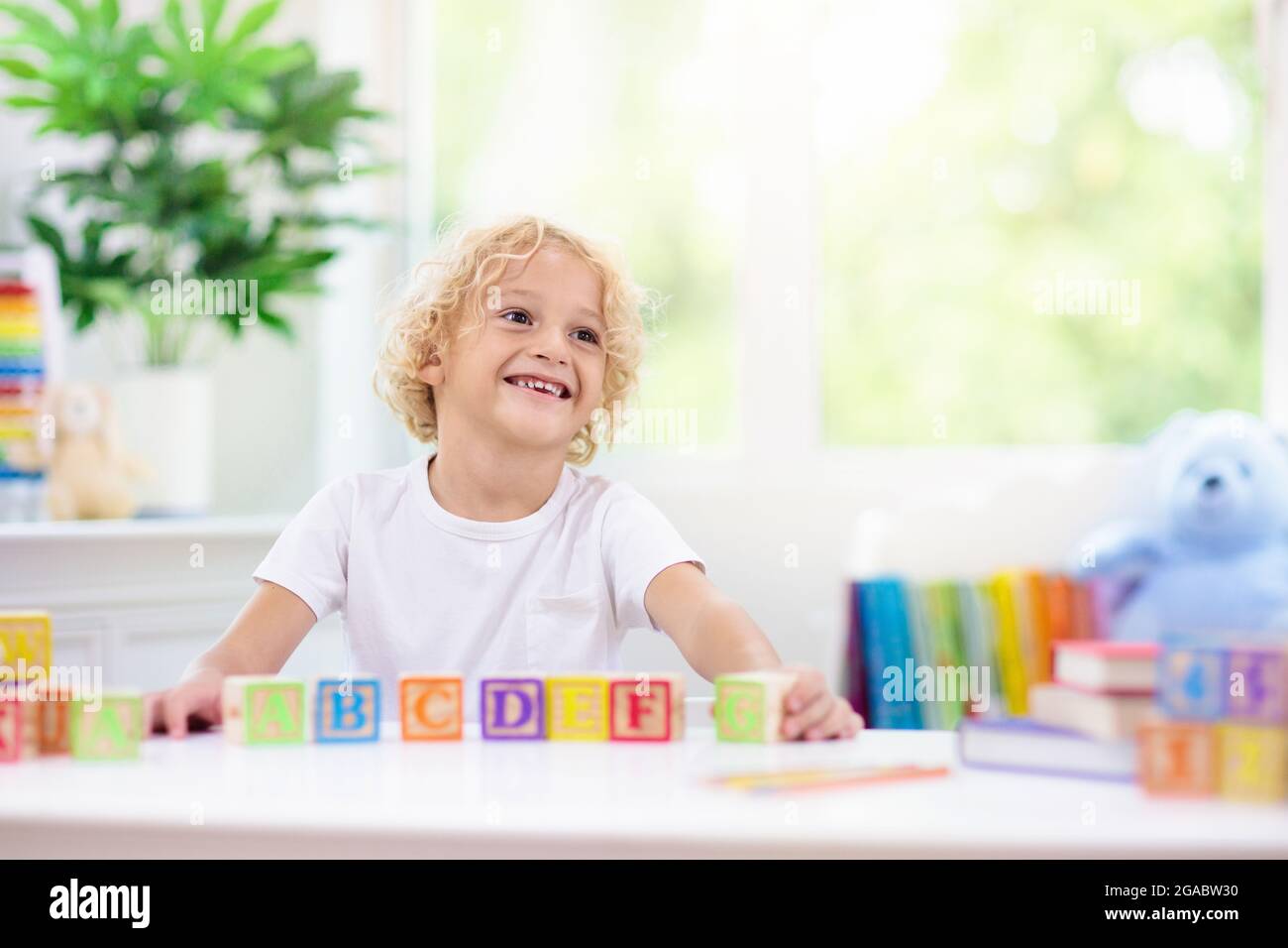 Child learning letters and numbers. Kid with colorful wooden abc blocks