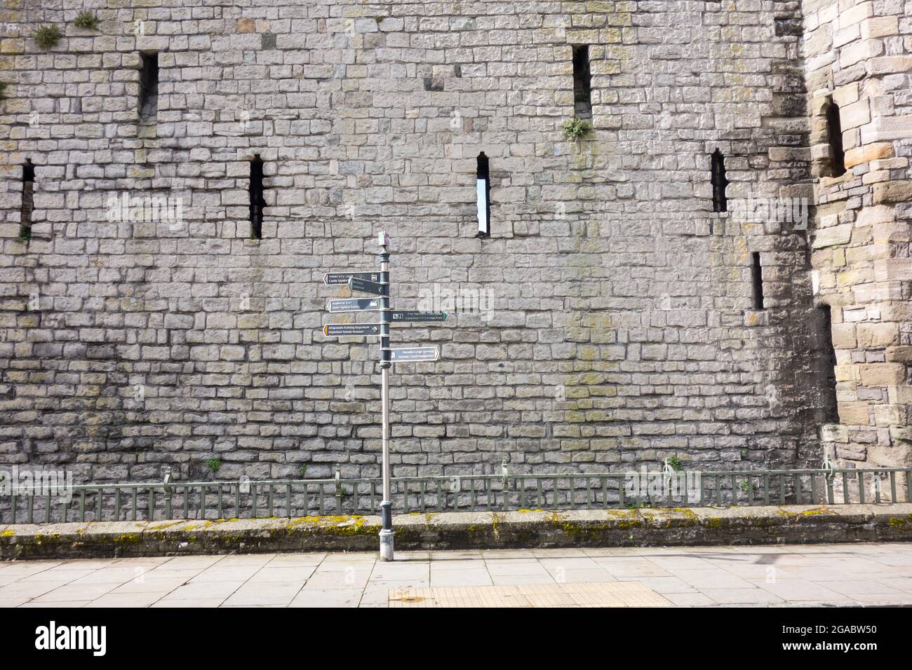 Sign post / way marker next to the castle wall in Caernarfon Wales UK Stock Photo