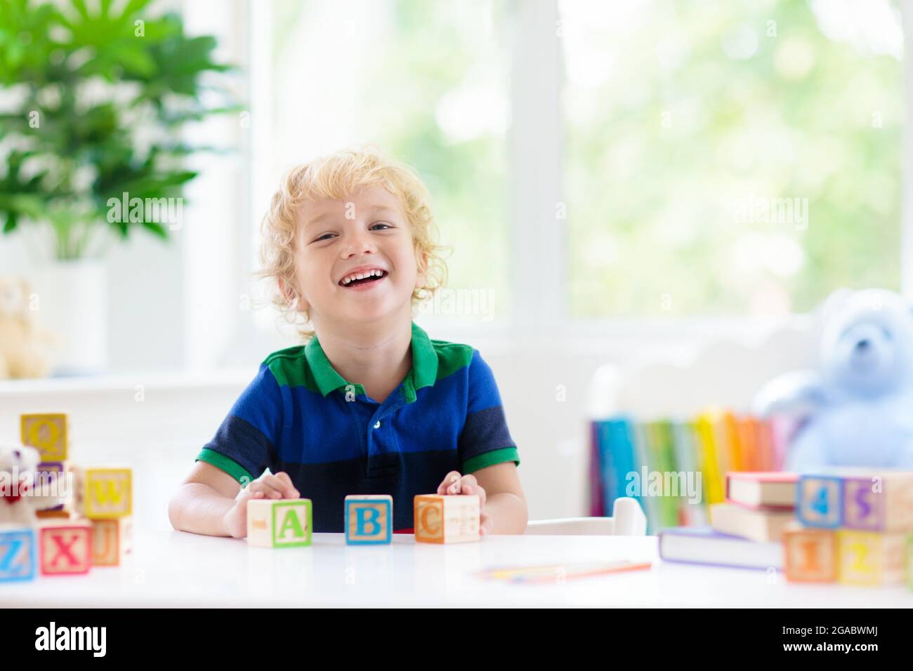 Child learning letters and numbers. Kid with colorful wooden abc blocks