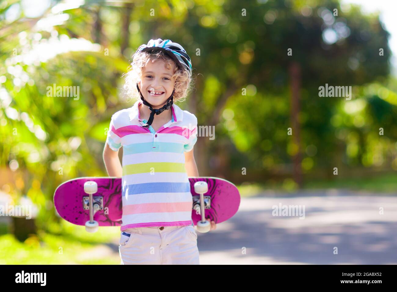 Kid with skateboard. Child riding skate board. Healthy sport and outdoor activity for school kids in summer. Sports fun. Helmet for safe exercise. Boy Stock Photo