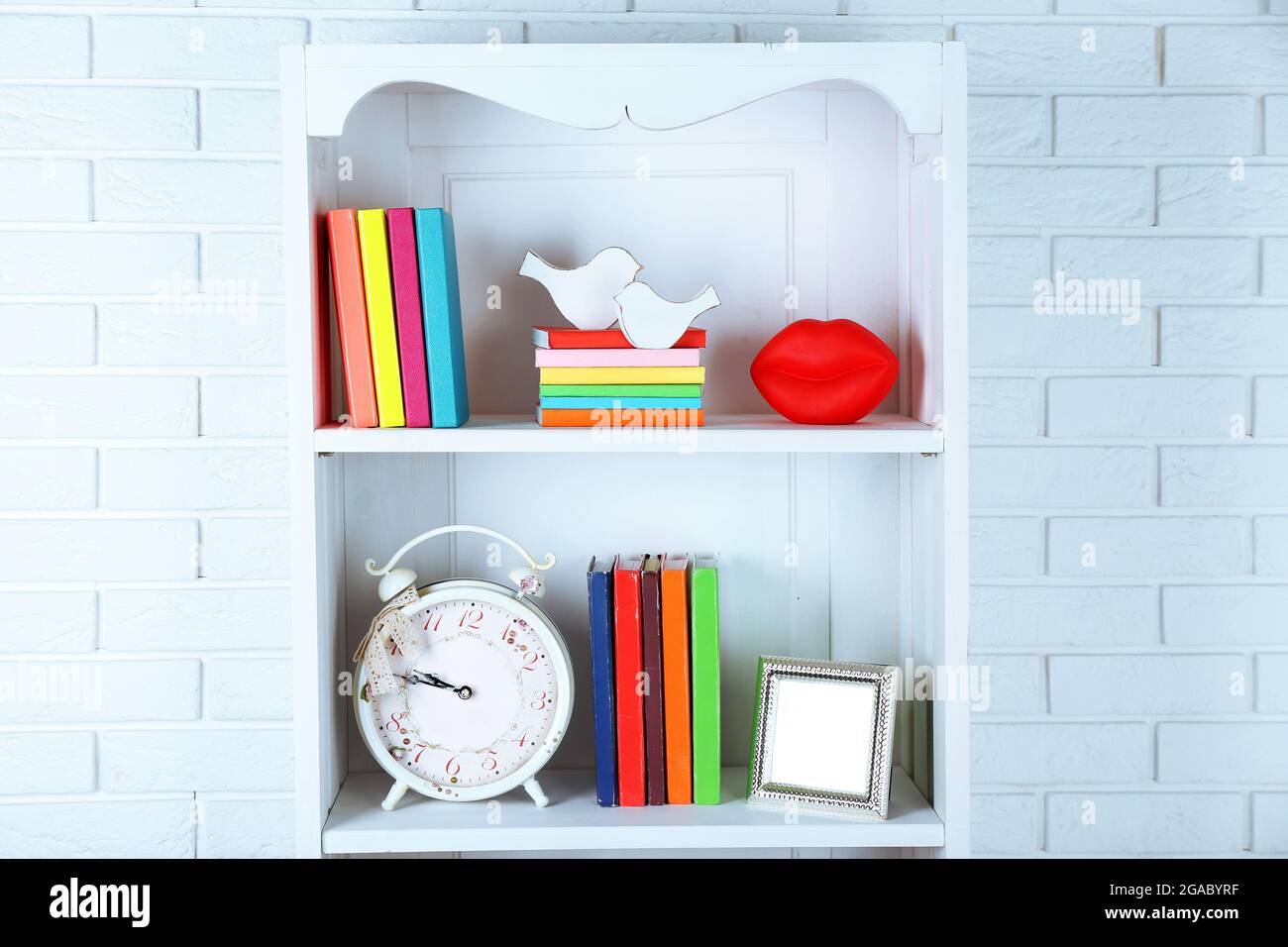 Books and decor on shelves in cupboard Stock Photo - Alamy