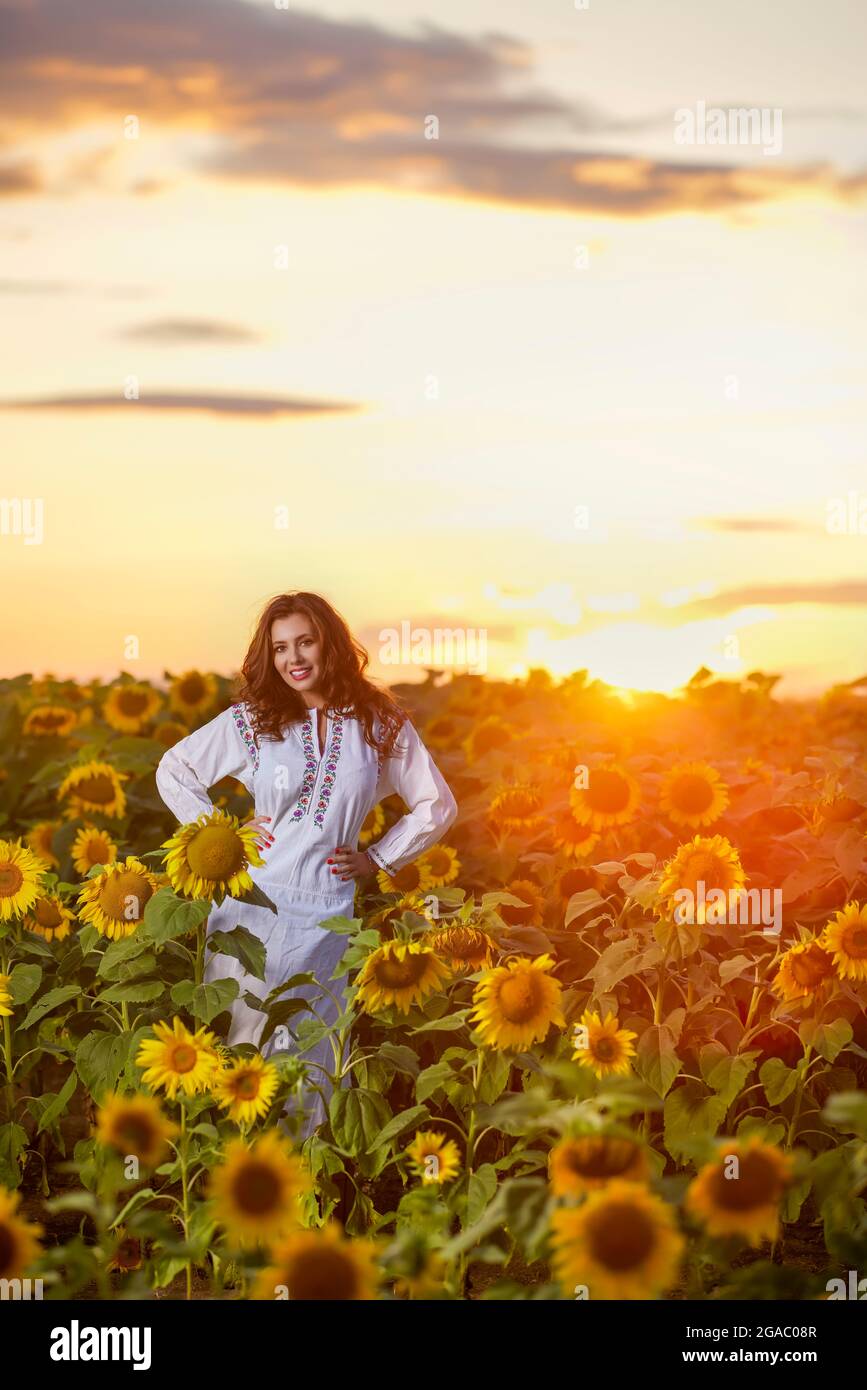 Beautiful woman enjoying nature in the sunflower field at sunset ...