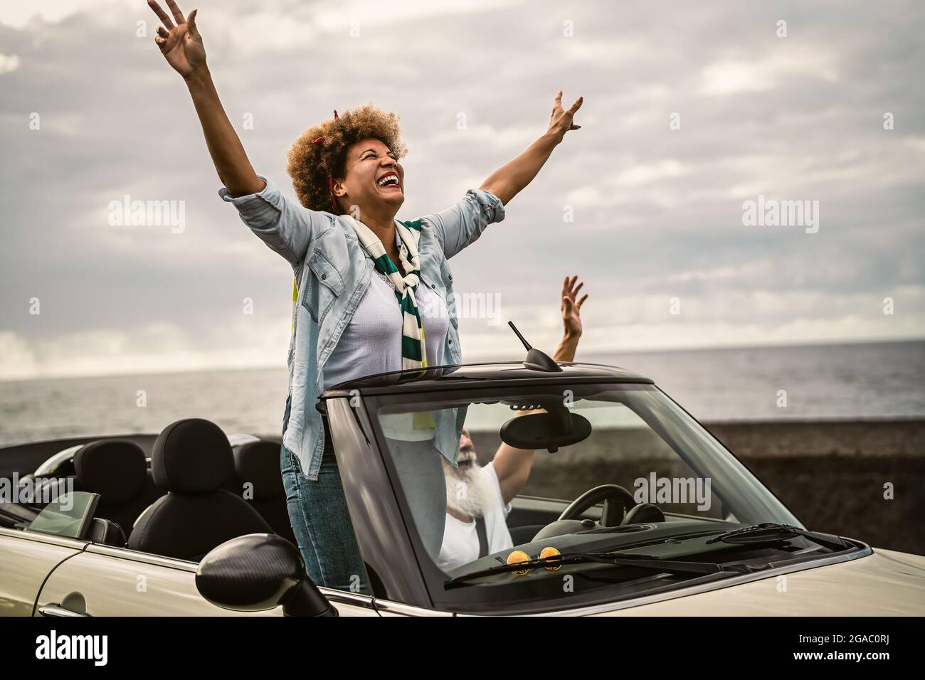 Happy senior couple having fun driving on new convertible car - Mature people enjoying time together during road trip tour vacation Stock Photo