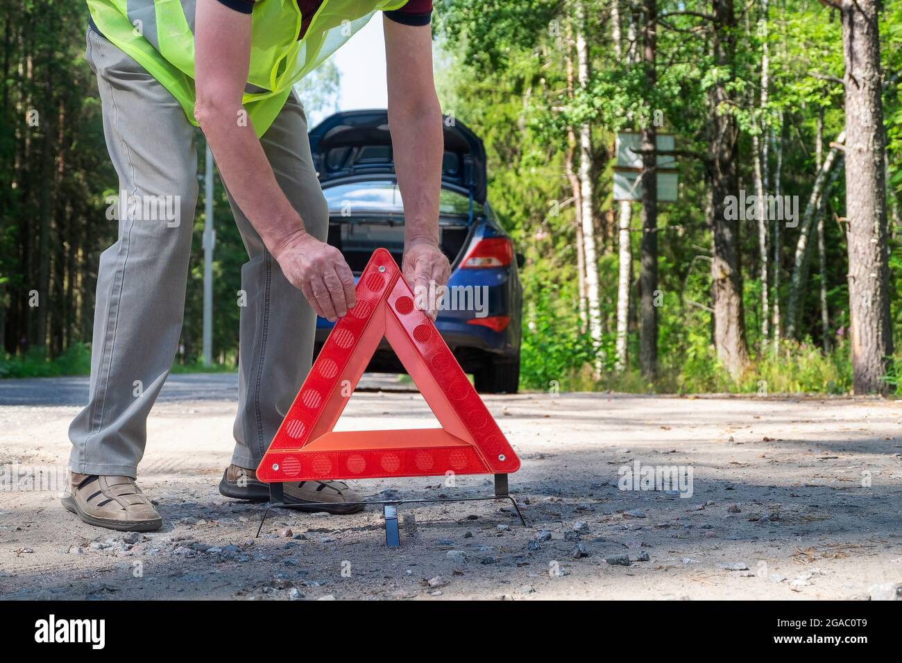 An adult man places a reflective red triangular warning triangle Stock Photo