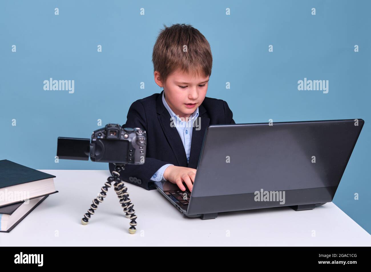 A Boy In A School Suit Writes With A Camera At A Computer During Distance Learning Copy Space On A Blue Studio Background Stock Photo Alamy