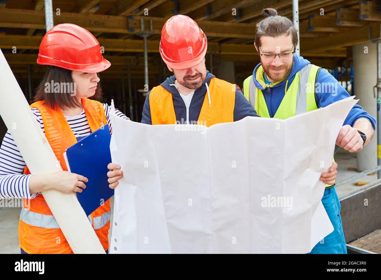 Architect and craftsman team with construction drawing on a new construction site during construction planning Stock Photo