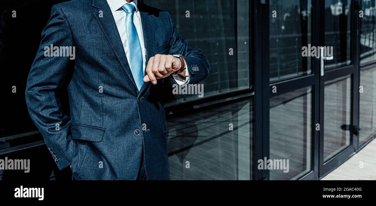 a banner with the image of a male silhouette in a business suit looks at the clock checks the time. Stock Photo