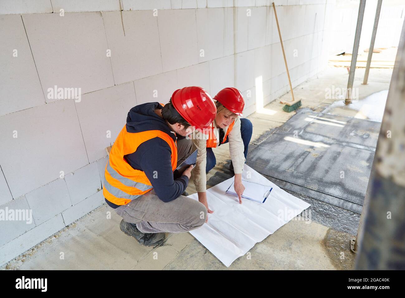 Craftsmen and architect with a blueprint in the shell of the construction site discuss the construction project Stock Photo