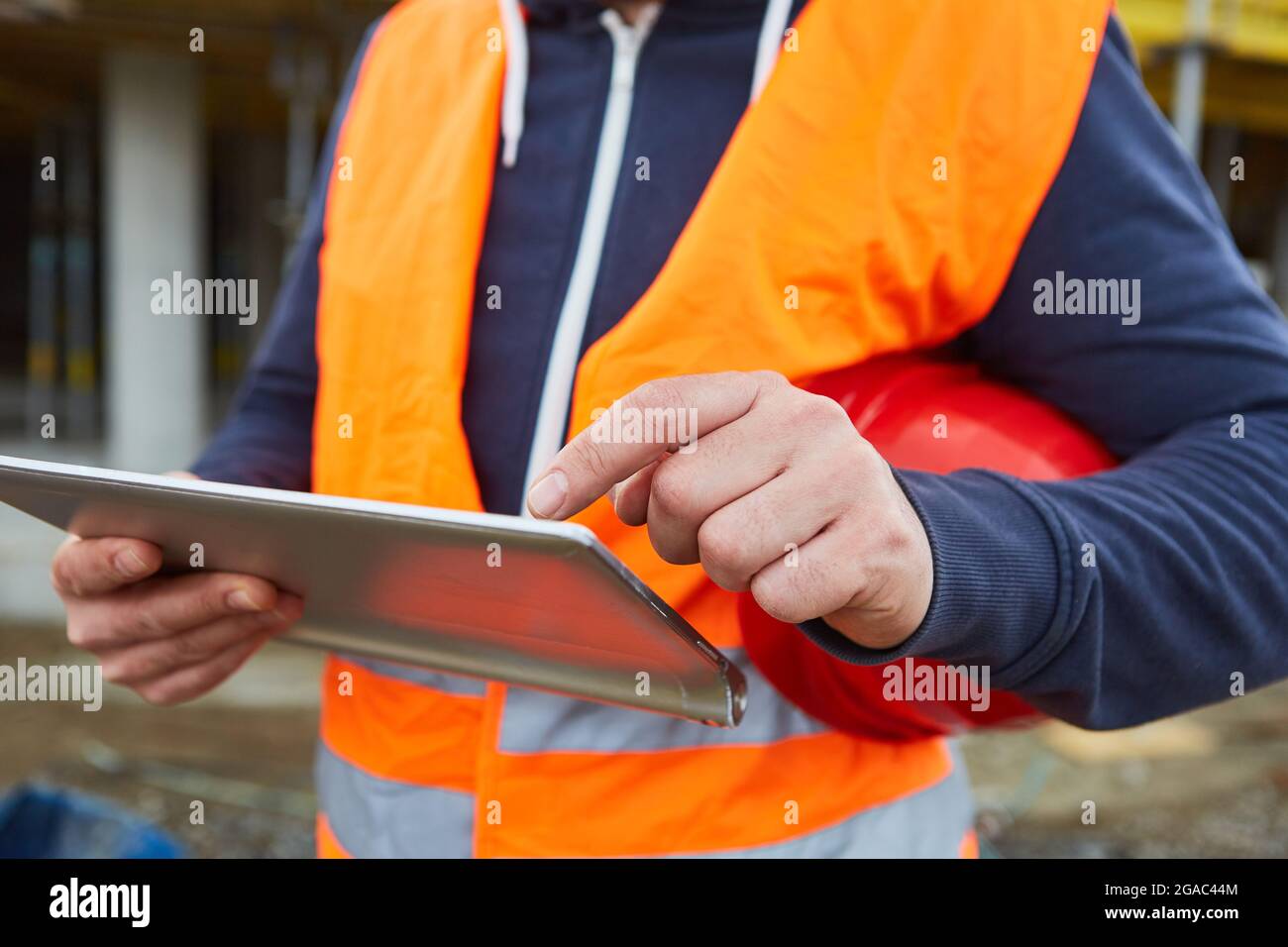 Hand of foreman operates touchscreen on tablet computer for planning a construction project Stock Photo