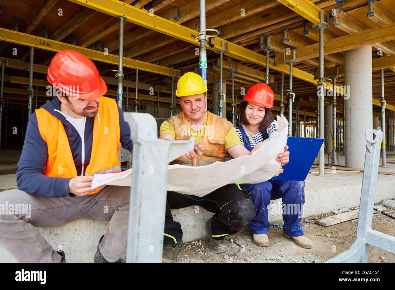 Architect and construction workers team with blueprint plan construction project on the construction site of house building Stock Photo