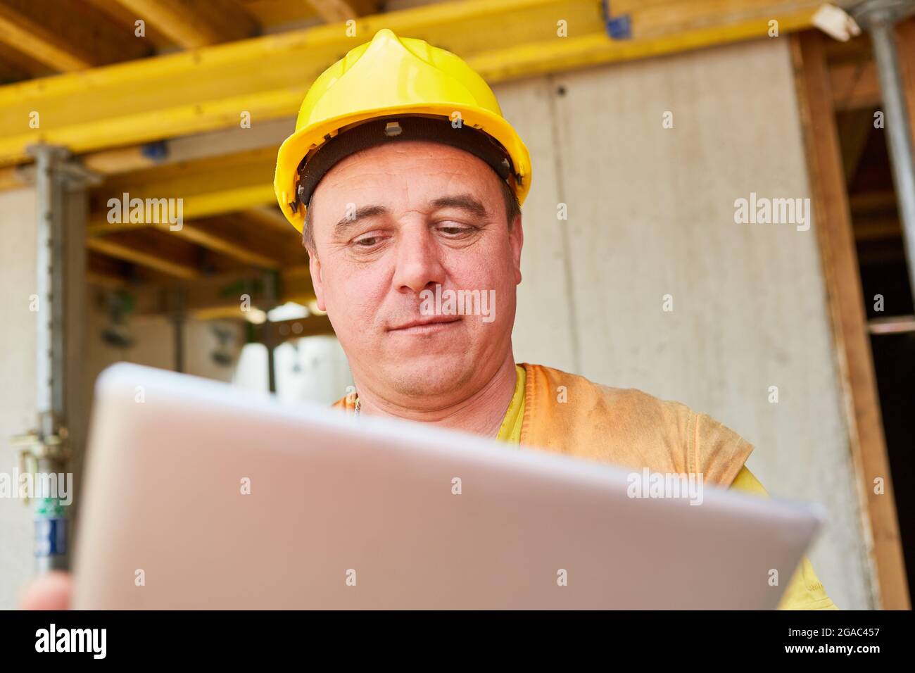 Construction worker as a foreman looks at tablet computer during house construction planning on the construction site Stock Photo