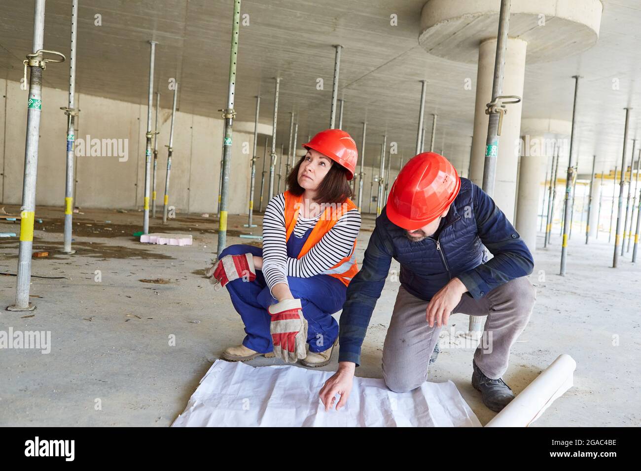 Architects team with a floor plan together during the construction planning on the construction site in the shell Stock Photo