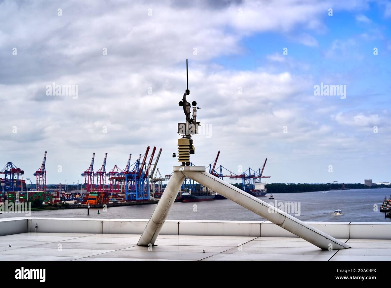 Weather station on the roof of an office building with the cranes of the container port in the background Stock Photo