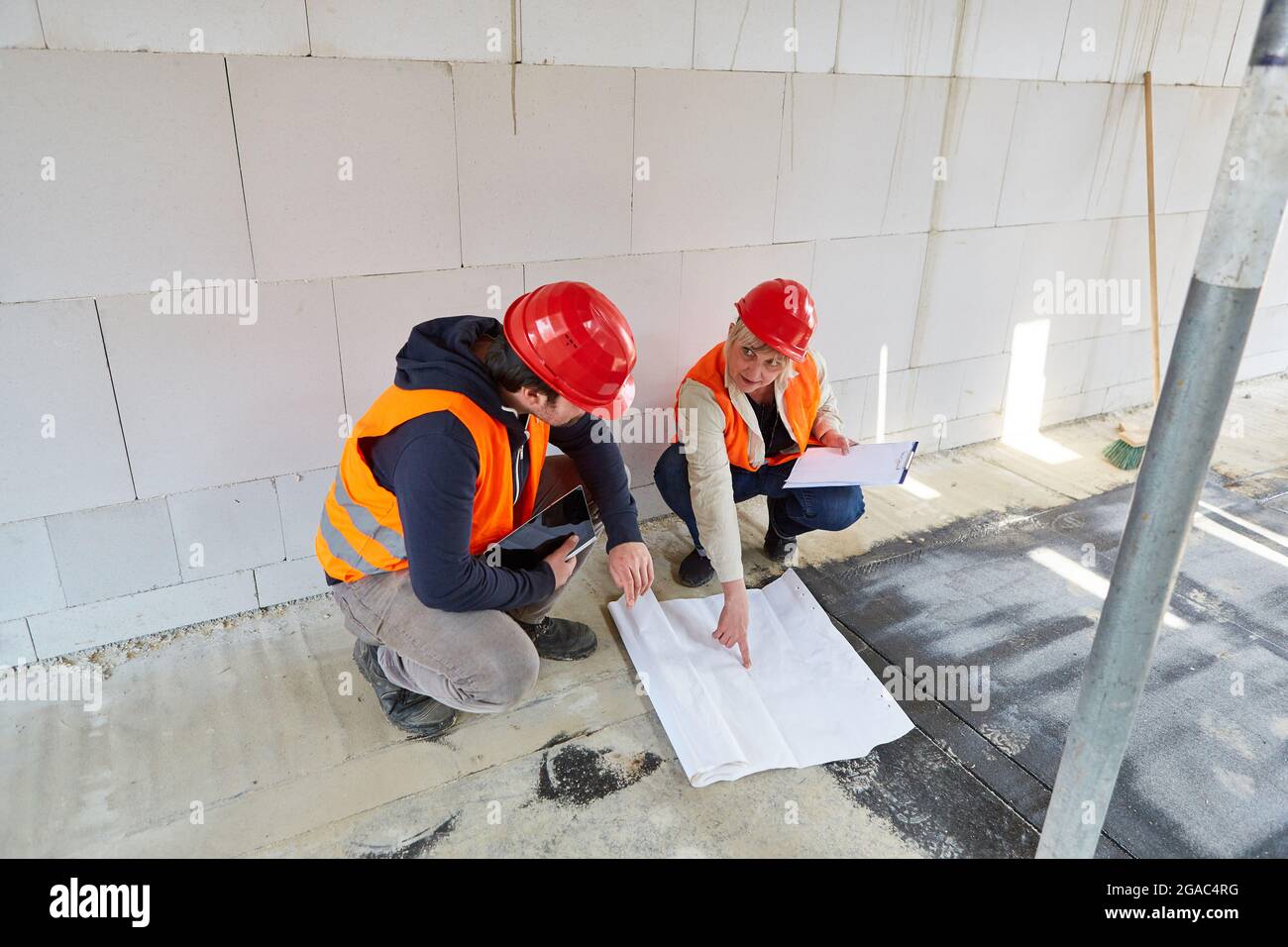 Architect and craftsman with construction drawing discuss construction project in the shell of the construction site Stock Photo