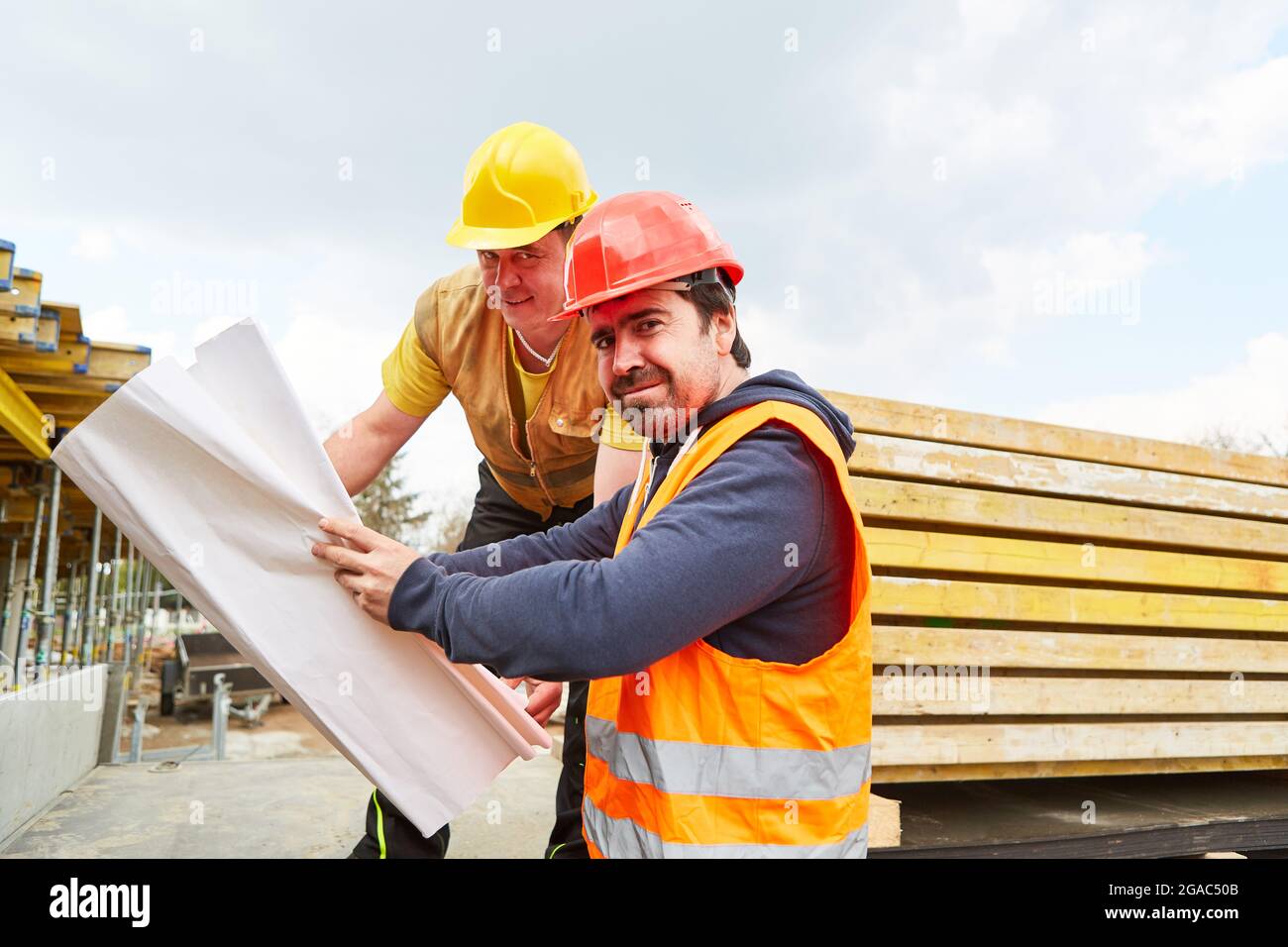 Architect and construction worker together on a construction site with floor plan during construction planning Stock Photo