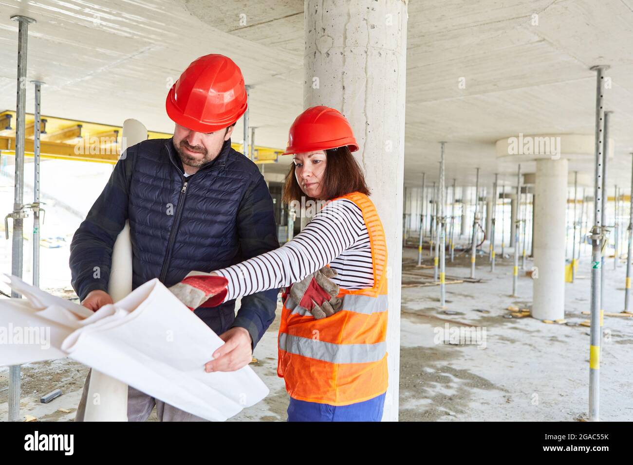 Craftsman and architect with construction plan together in the shell of the construction site of the house construction Stock Photo
