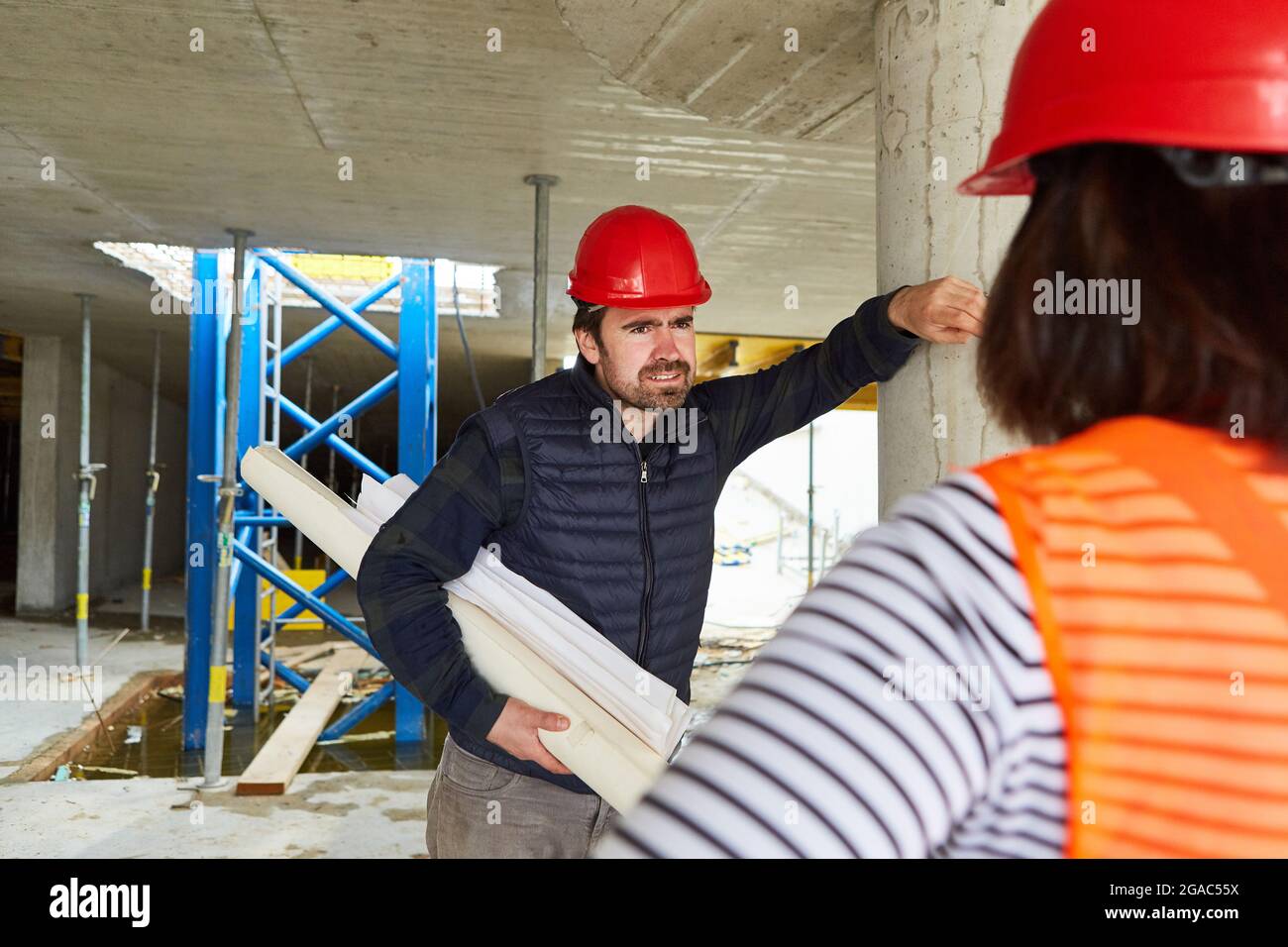 Craftsman and architect with construction drawing together in the shell construction during construction planning Stock Photo