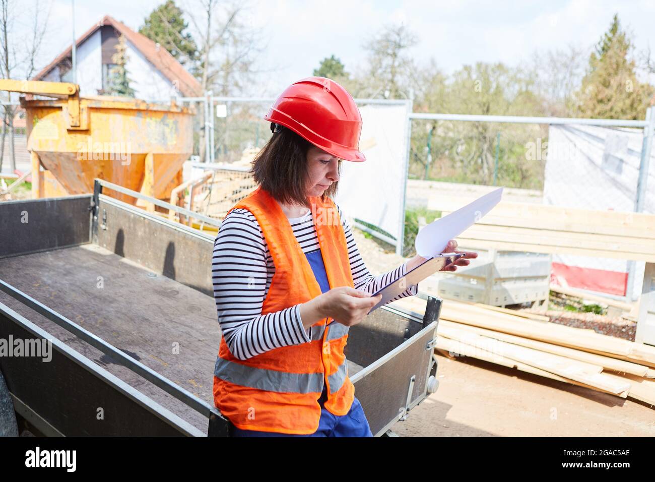 Woman as an architect with protective helmet on a construction site looks at checklist for construction planning Stock Photo