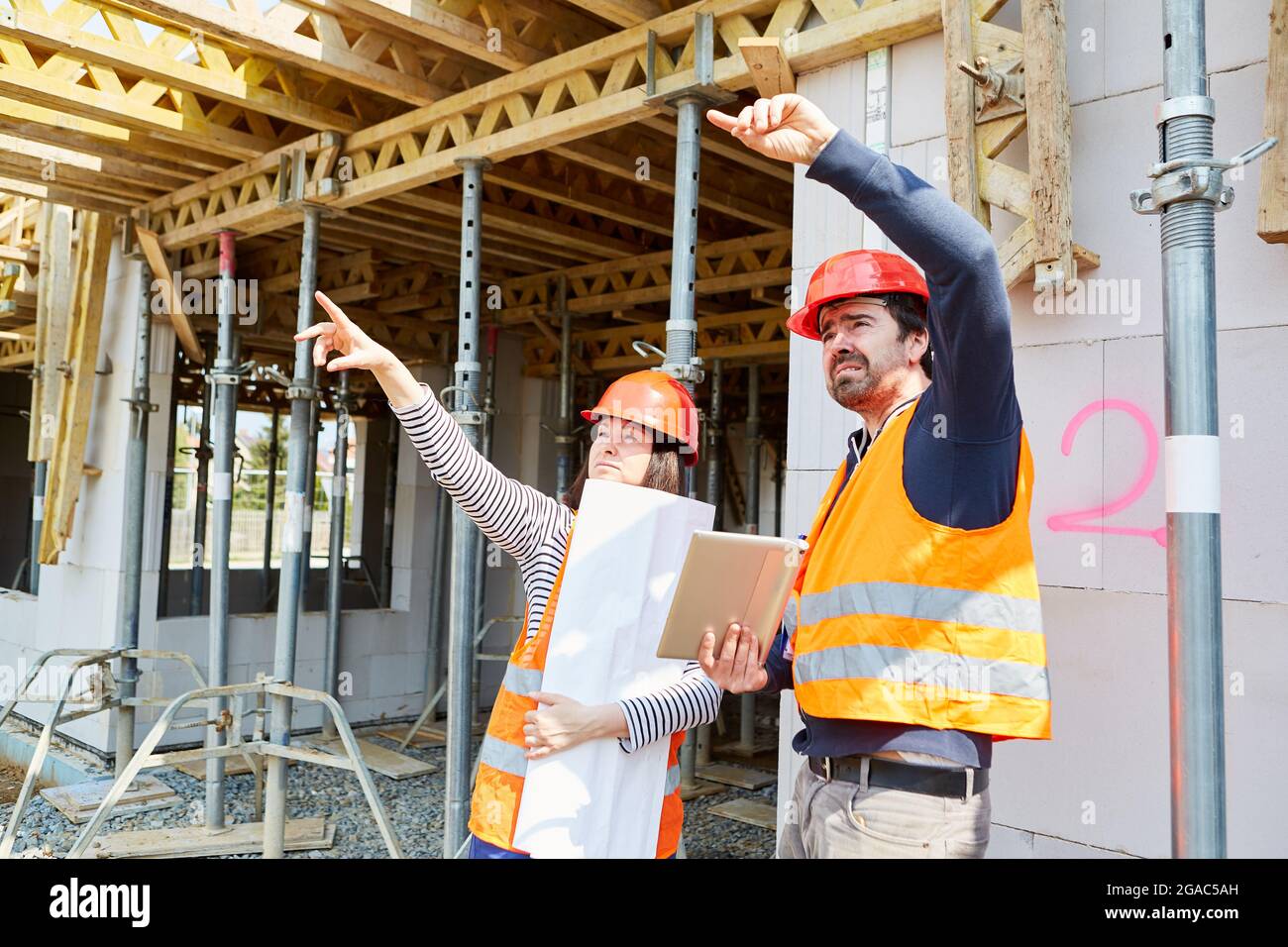 Craftsmen and architects with construction plan discuss organization and construction planning prior to the shell construction Stock Photo