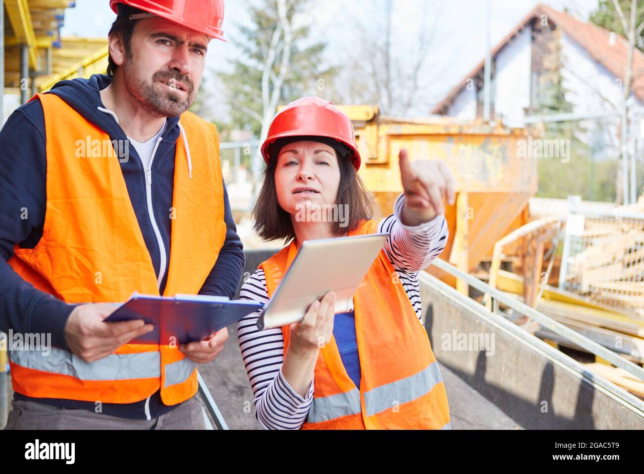 Worker and architect using tablet computer together during construction planning on construction site Stock Photo
