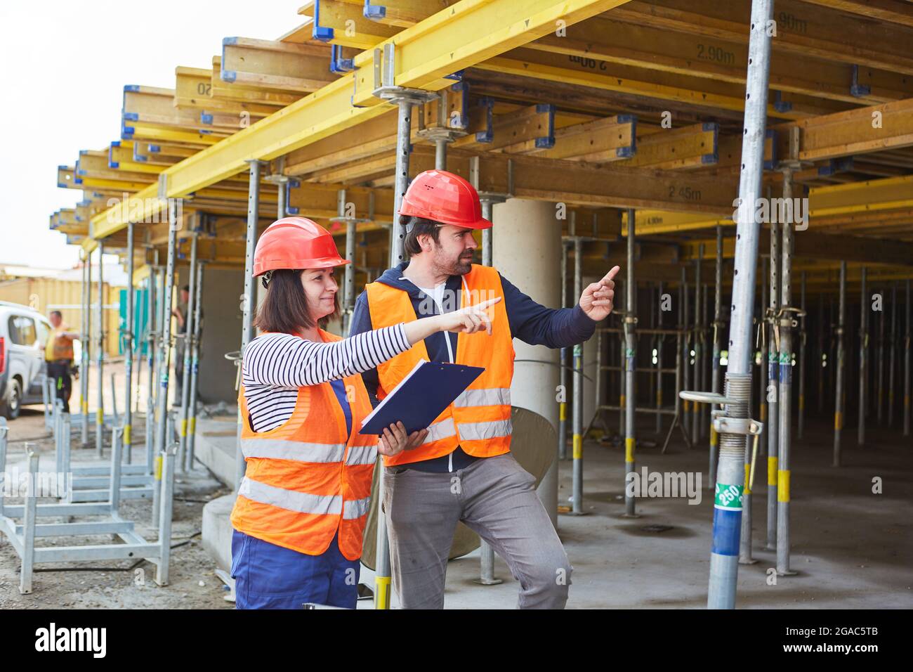 Architect with checklist and craftsman discuss construction planning in front of the shell construction site Stock Photo