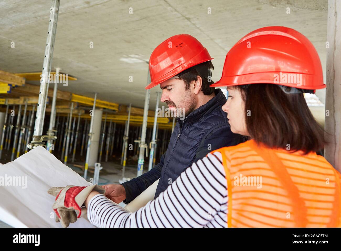 Craftsman and architect with floor plan during the construction planning in the shell of the construction site of the house construction Stock Photo
