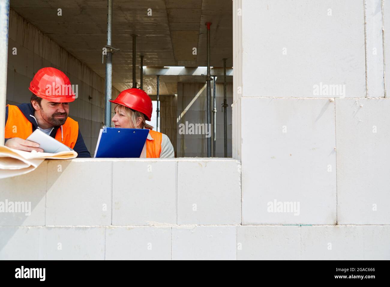 Architect with checklist and foreman discuss construction project on the construction site in the shell Stock Photo
